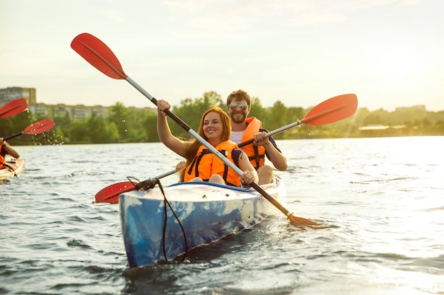 Premium Photo | Happy young caucasian couple kayaking on river with sunset in the backgrounds. Having fun in leisure activity. Happy male and female model laughting on the kayak. Sport, relations concept.