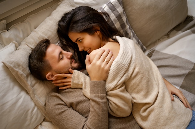 Hermosa joven pareja feliz descansando en la cama y sonriendo, abrazando | Foto Gratis