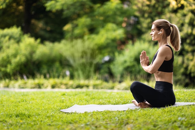 Mulher tranquila e bem ajustada meditando no espaço de cópia do parque público | Foto Premium